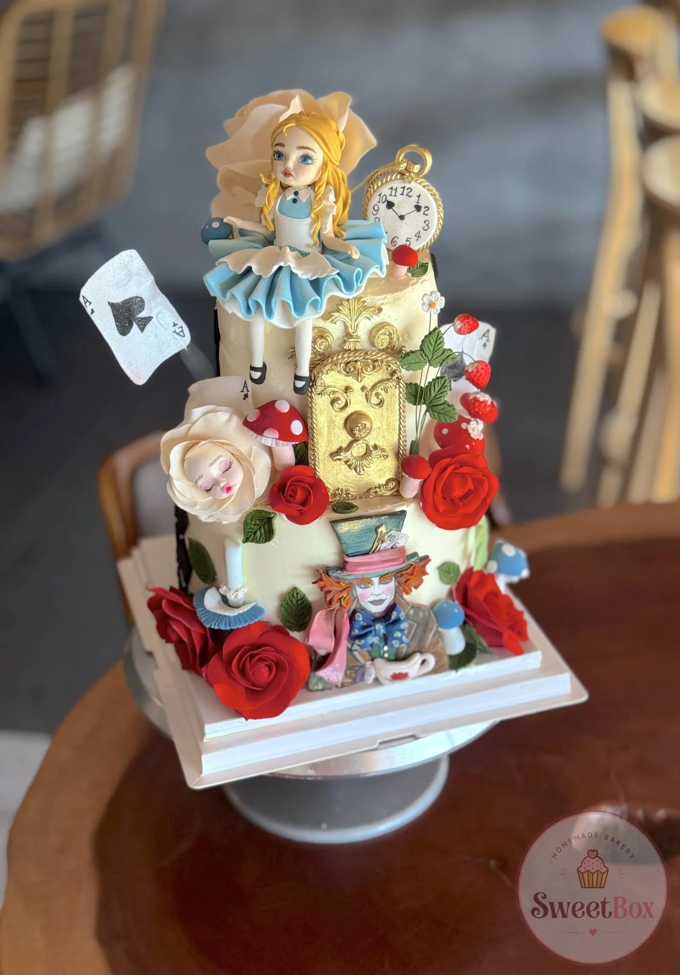 Alice in Wonderland tiered cake with Alice, the Mad Hatter, red roses, a clock and playing cards
