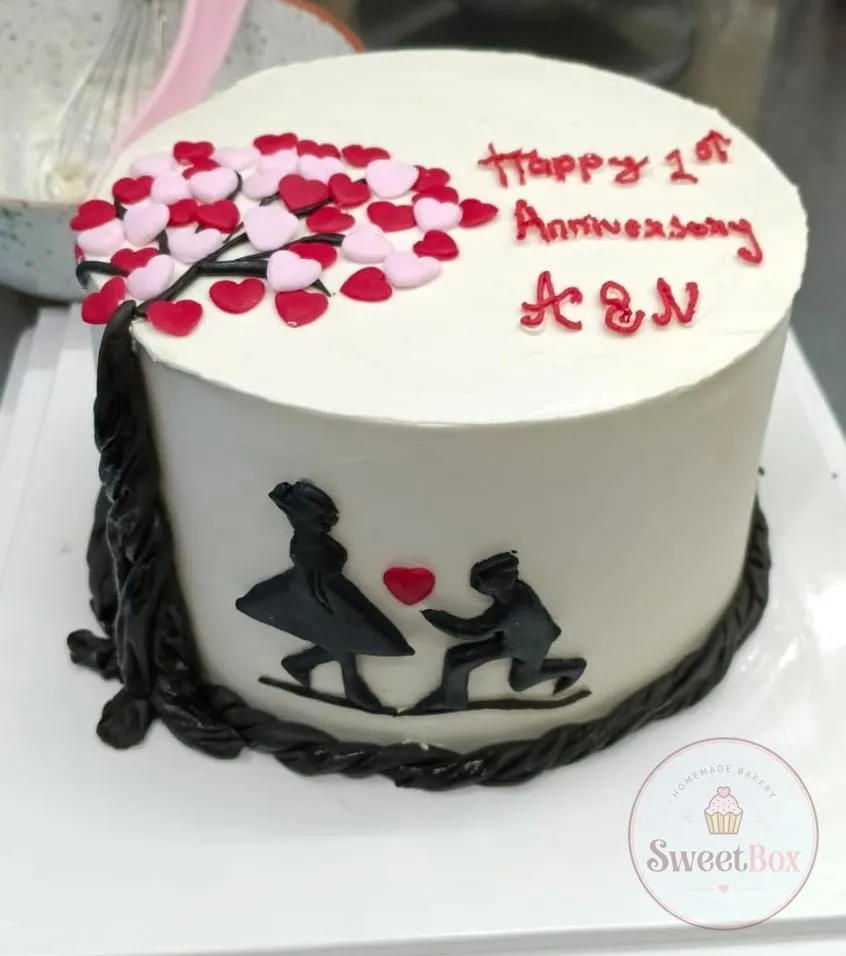 Happy 1st Anniversary cake with a pink heart tree and a black silhouette of a marriage proposal