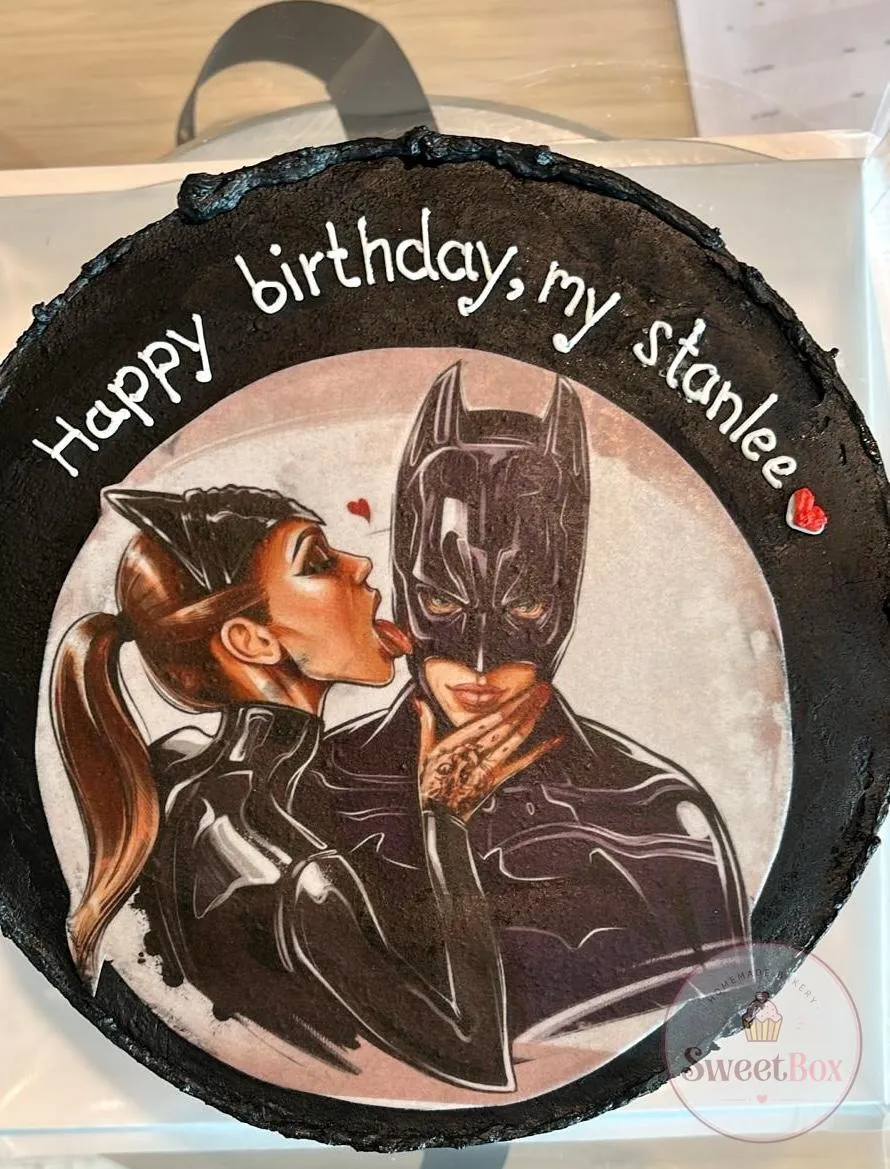 Black photo cake with a Batman and Catwoman kiss illustration and a personalized Happy Birthday message