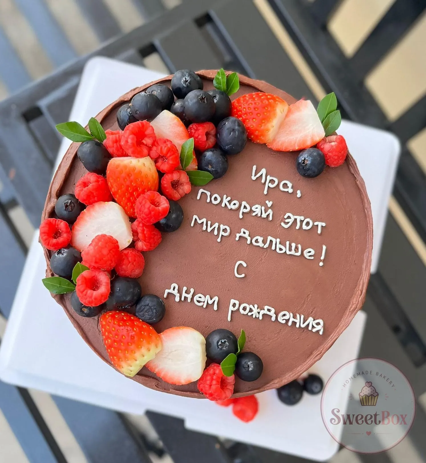 Chocolate cake with strawberries, raspberries and blueberries around a piped birthday message on top