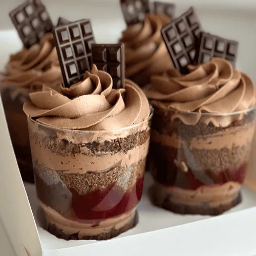 Layered chocolate trifle cups with chocolate cream swirls and chocolate bar pieces on top