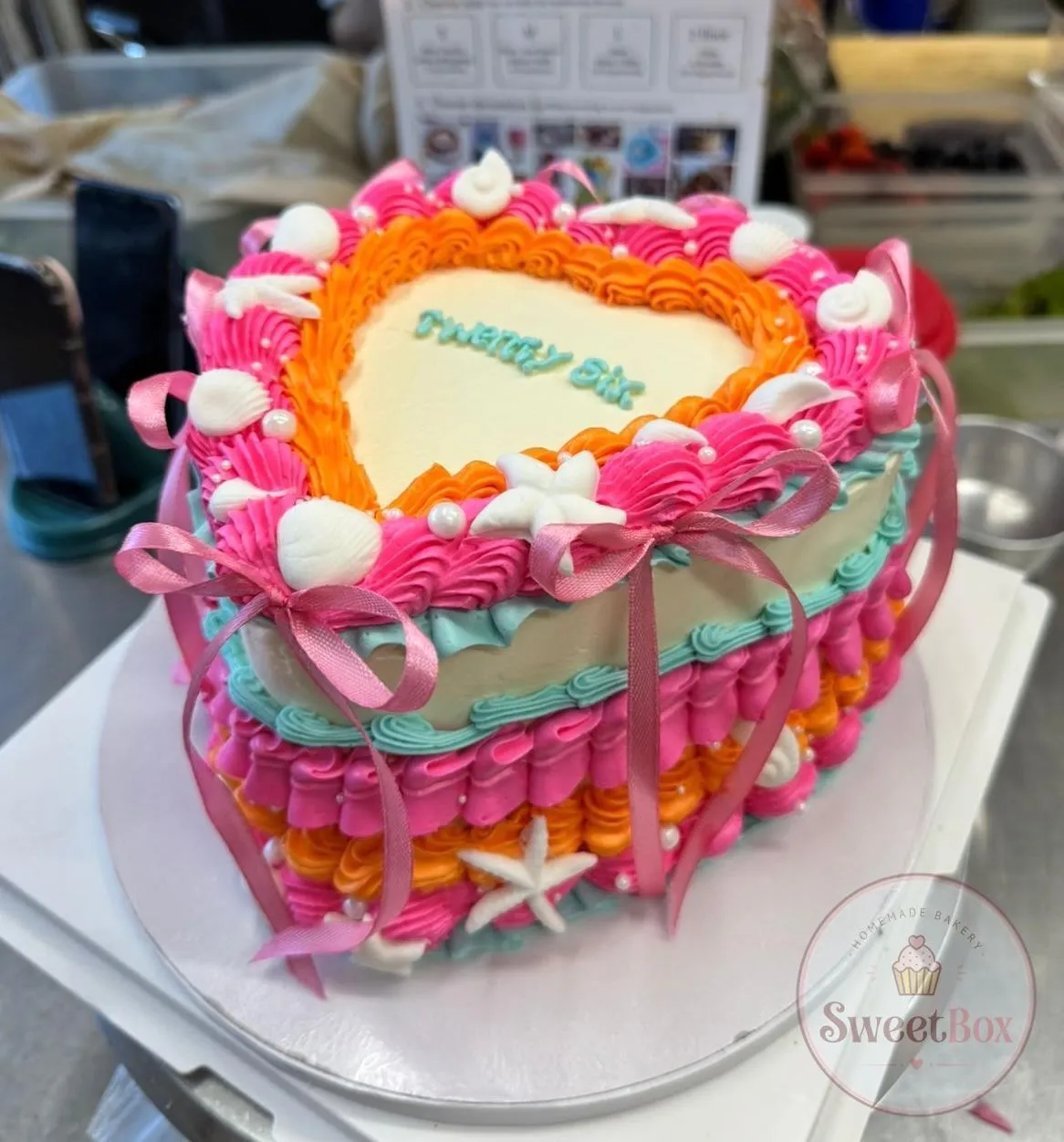Bright pink, orange and turquoise heart cake with seashells, starfish and pink ribbon bows
