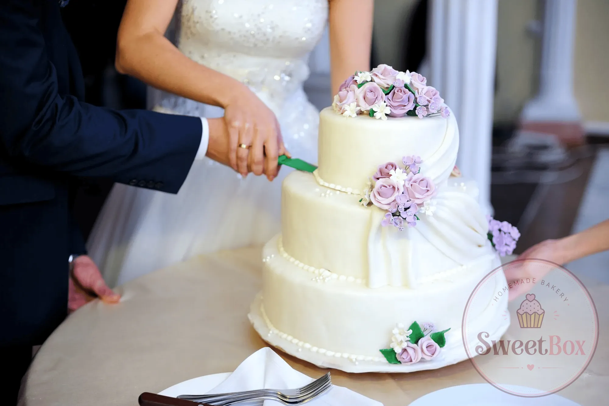 Bride and groom cutting a three-tier ivory wedding cake decorated with lilac flowers
