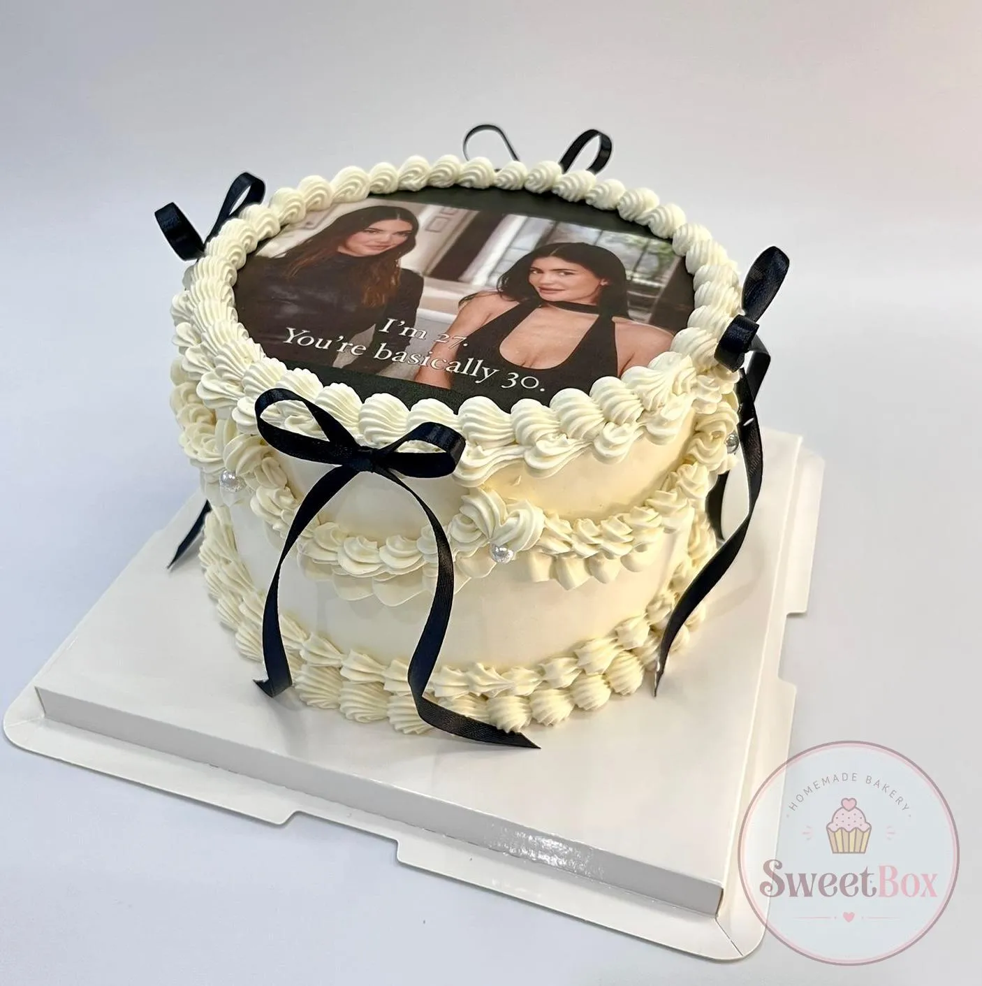 Cream vintage photo cake with an edible portrait print, ruffled piping and black ribbon bows