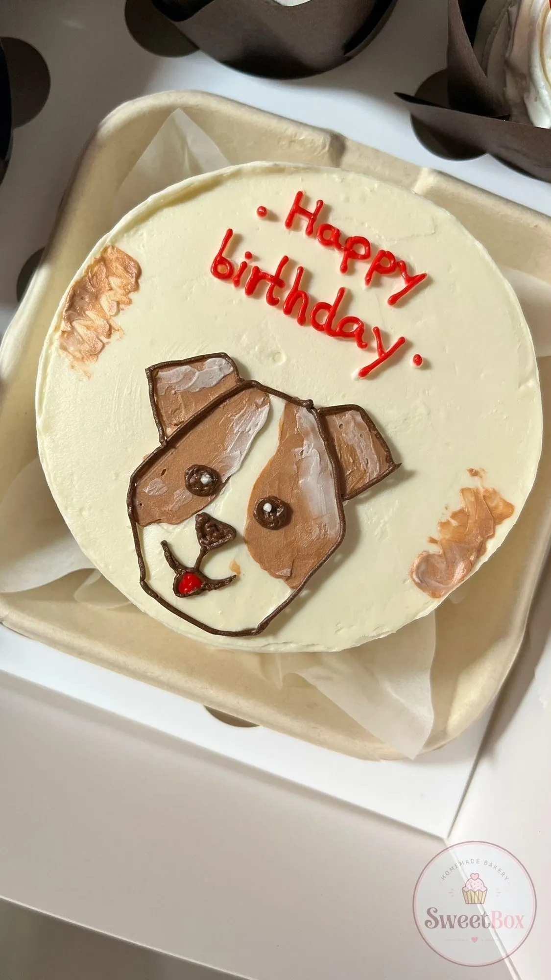 White bento cake with a hand-drawn brown and white dog and red Happy Birthday lettering