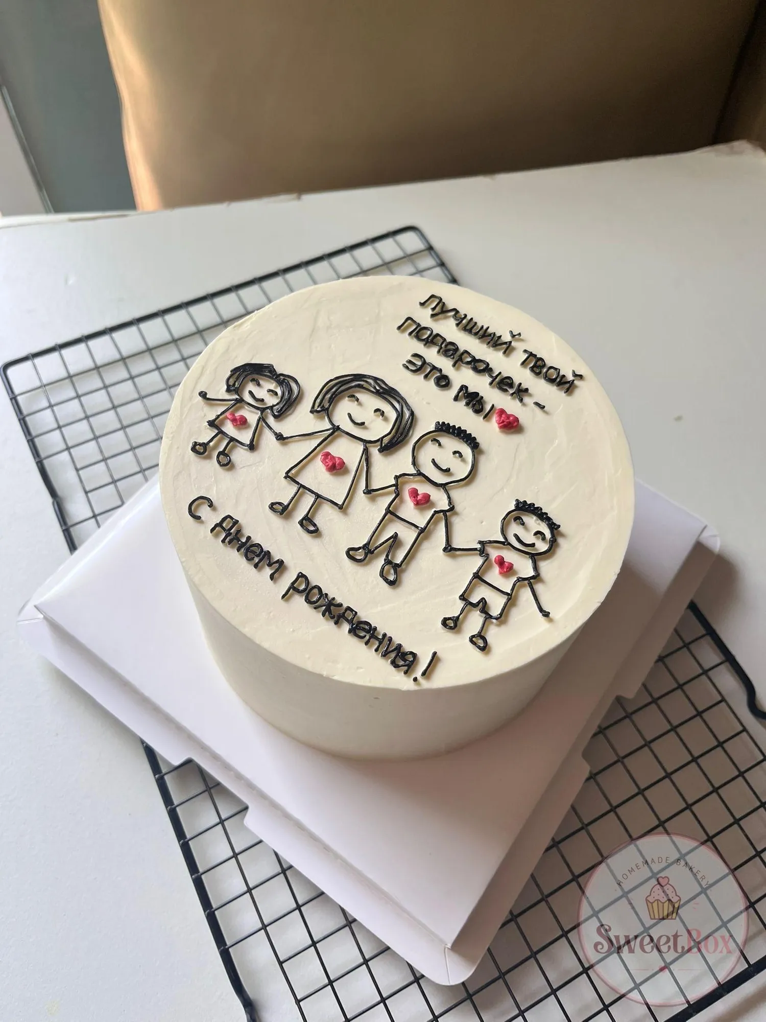 White bento cake with a drawn family of four holding hands and a birthday message in Russian