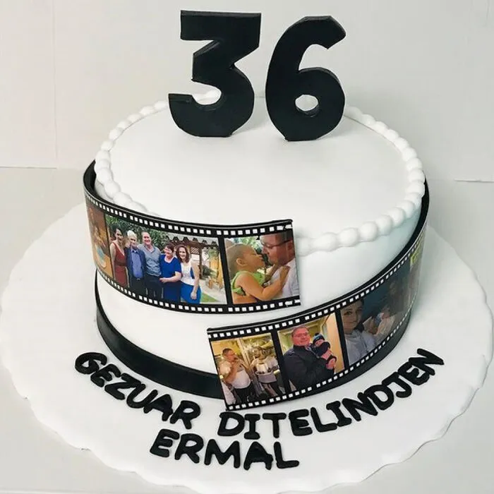 White cake with an edible film strip of family photos, a black number 36 and a birthday greeting in Albanian