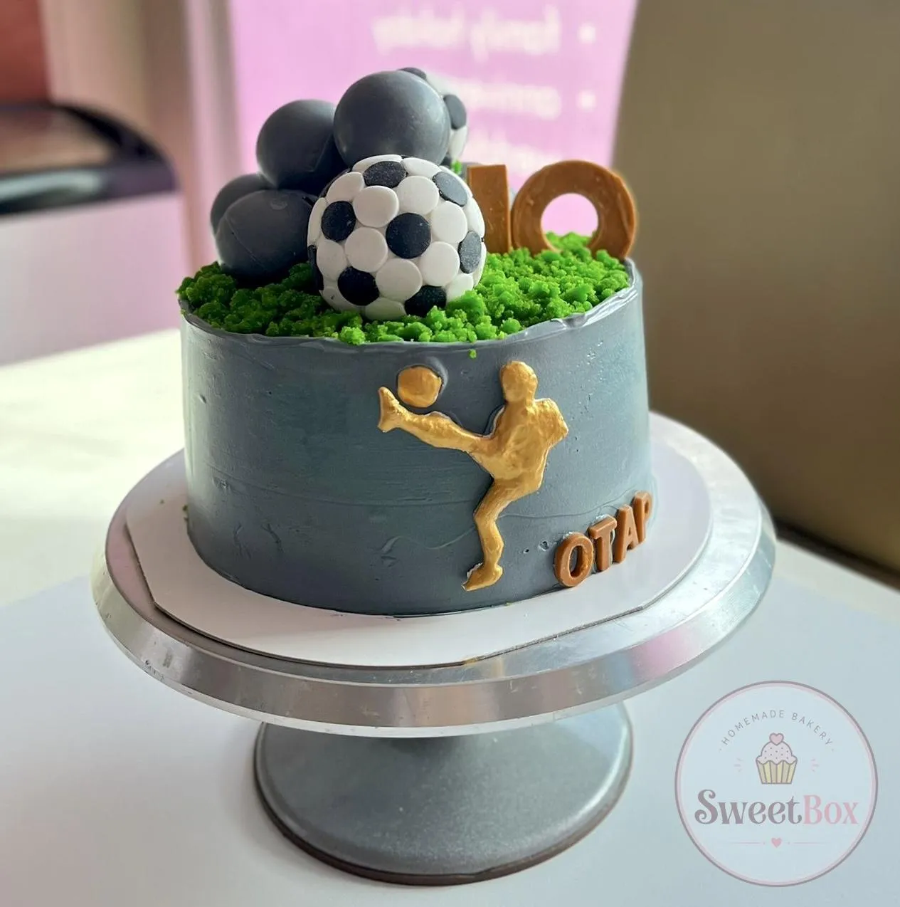 Gray soccer birthday cake with a fondant ball, green grass top, number 10 and gold player figure