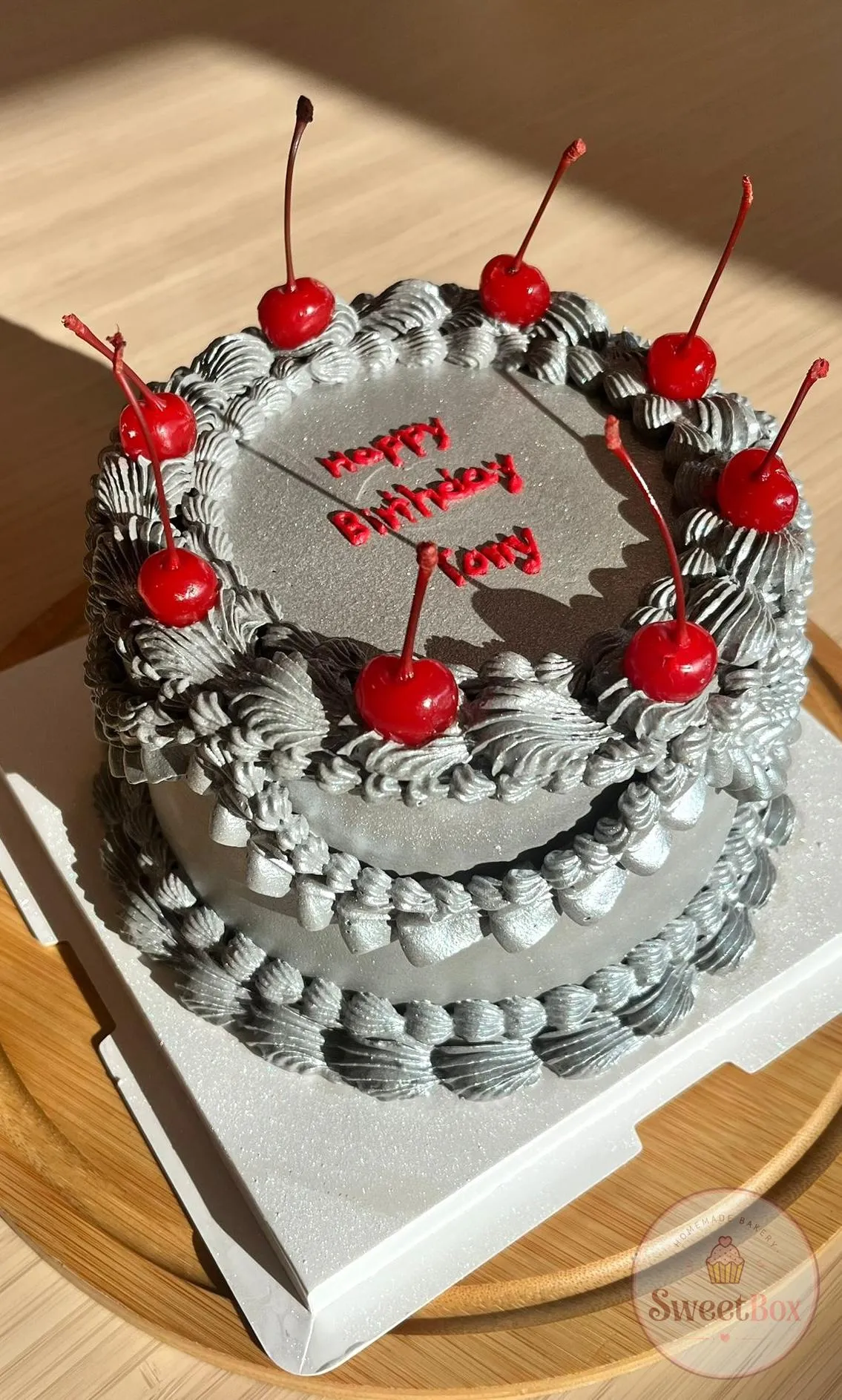 Gray vintage birthday cake with piped ruffles, red birthday script and cherries on top