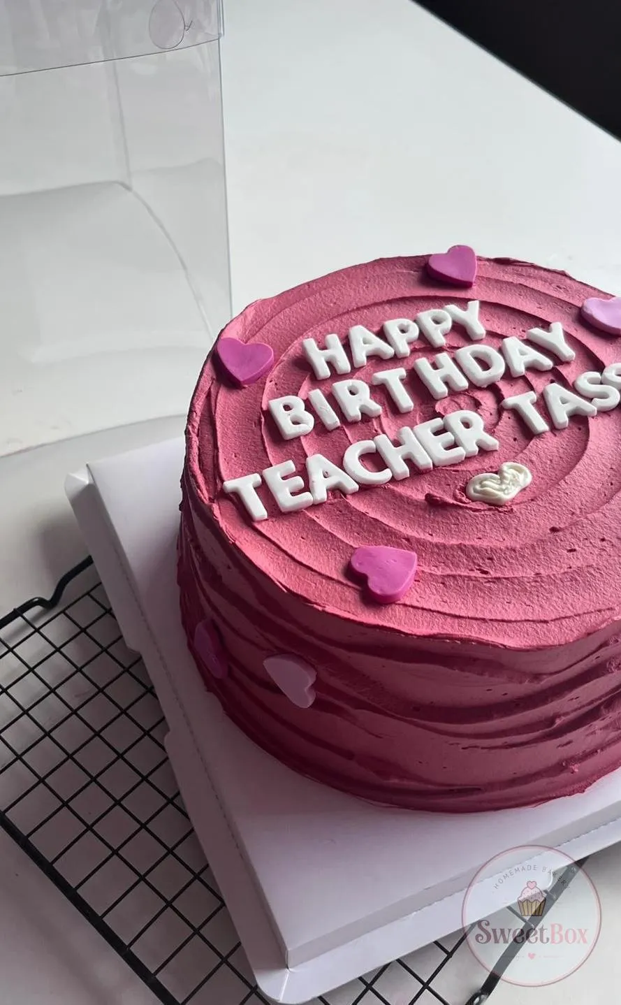 Magenta textured cake with white Happy Birthday Teacher letters and small pink hearts