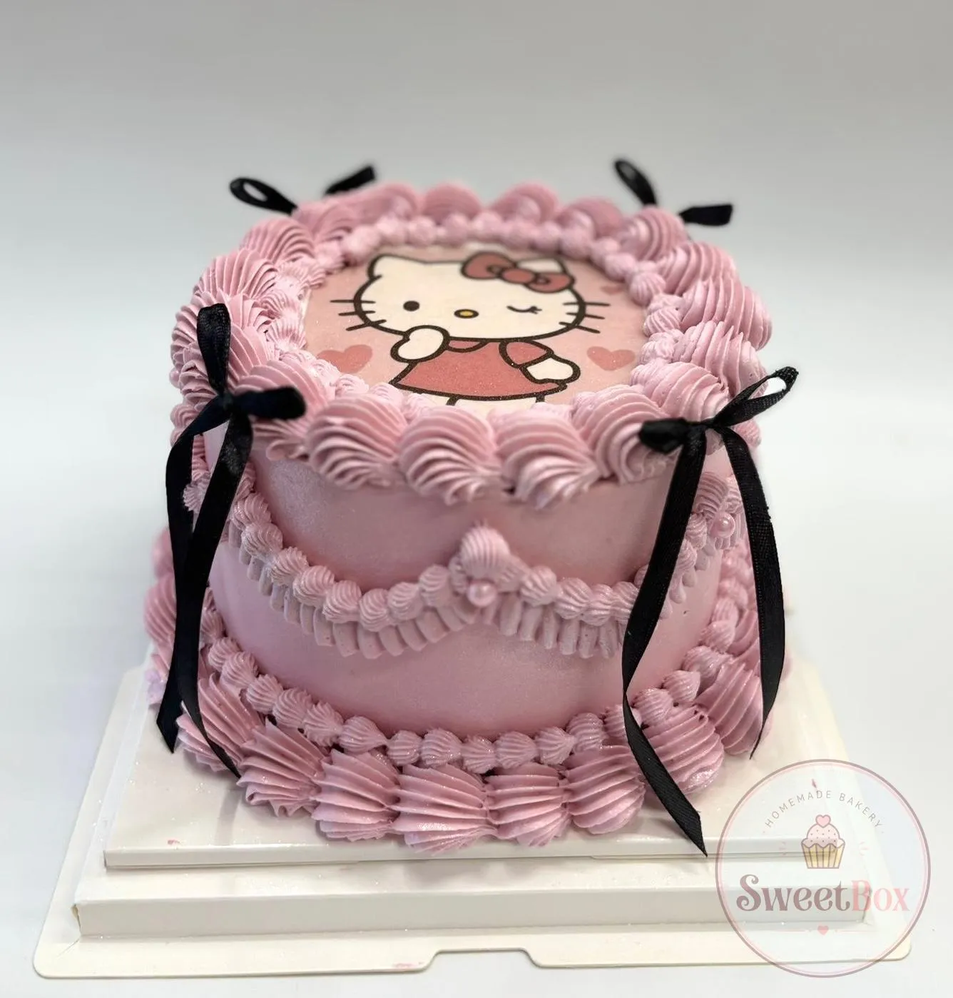 Pink vintage cake with a Hello Kitty edible print, ruffled piping and black ribbon bows