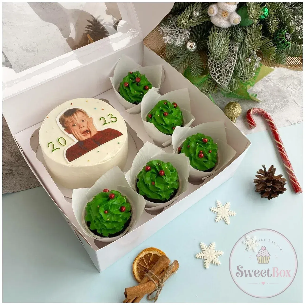 Christmas gift box with a Home Alone Kevin bento cake dated 2023 and green tree cupcakes