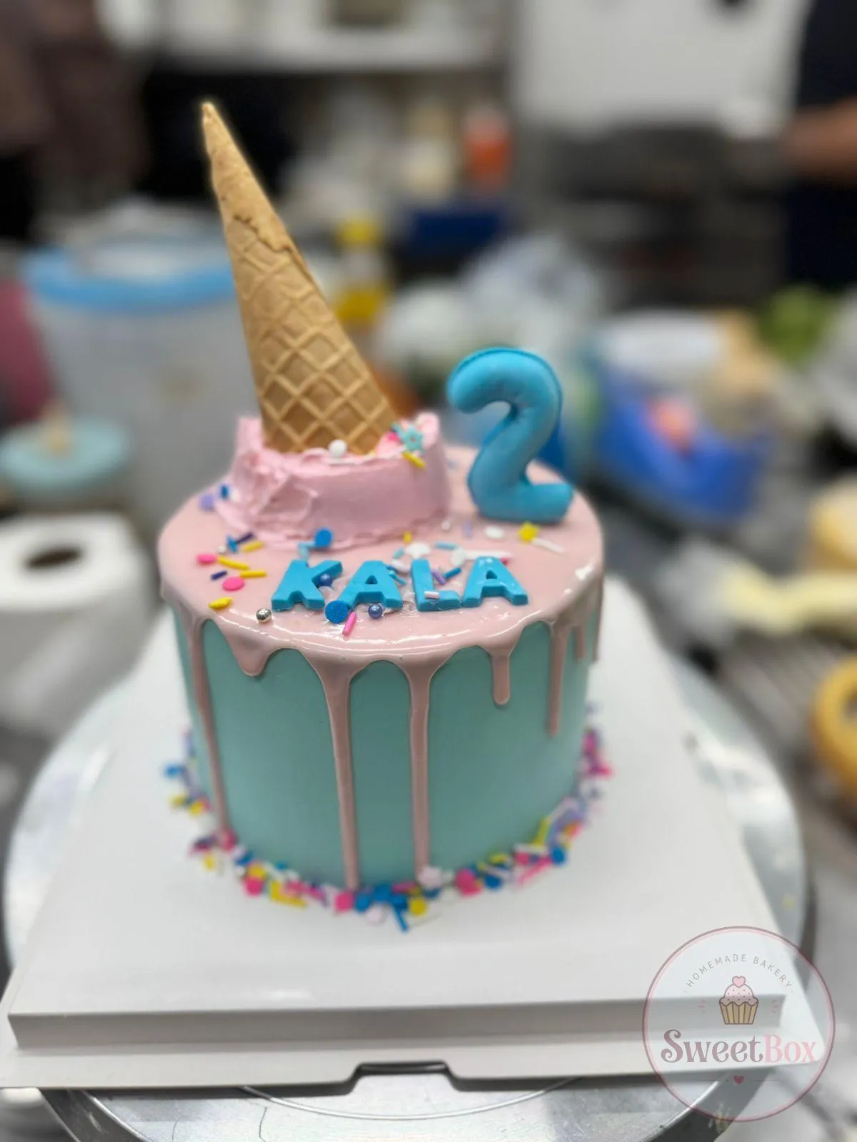 Blue and pink drip cake with an upside-down ice cream cone, sprinkles and number 2