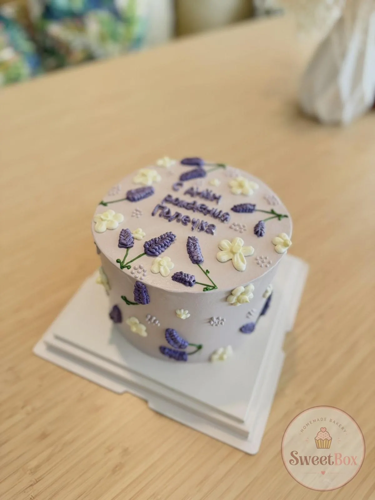 Lilac bento cake with piped lavender sprigs, white blossoms and a handwritten birthday greeting