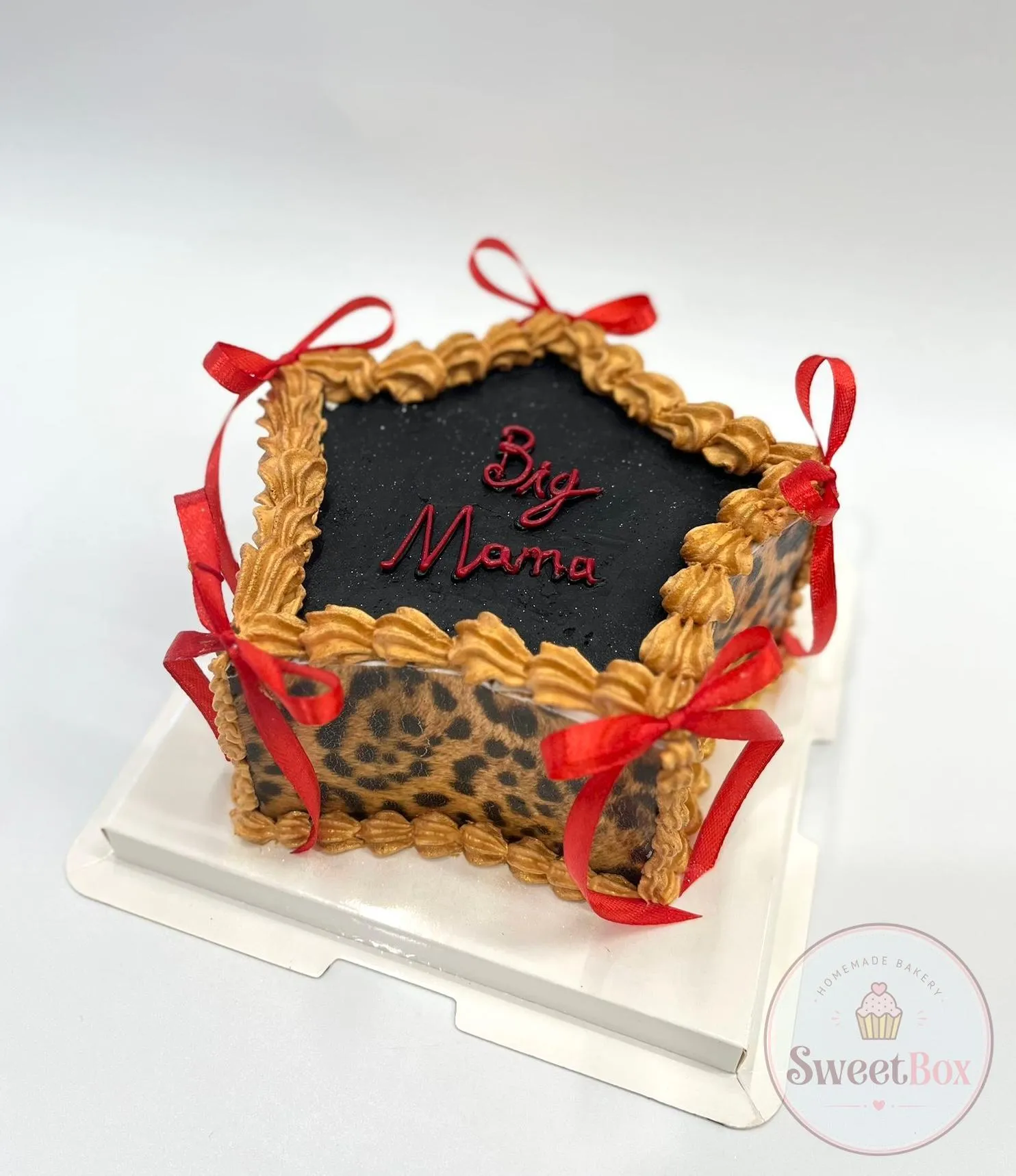 Square leopard-print cake with a black top, gold piped border, red ribbon bows and Big Mama written in red