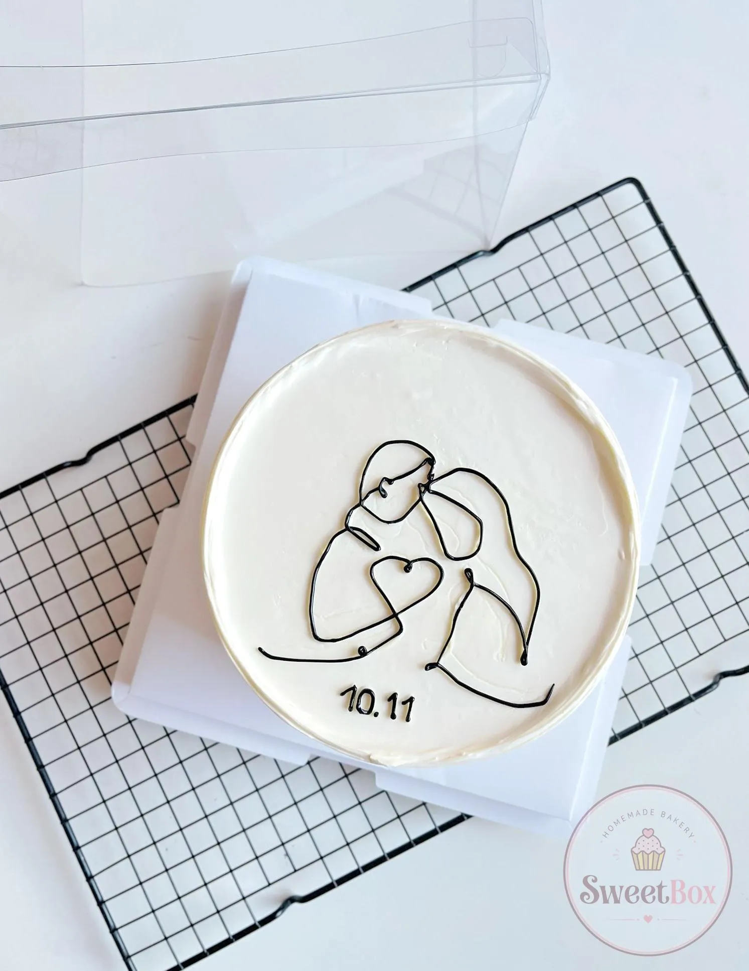 White cake with a black line drawing of an embracing couple, a small heart and the date 10.11