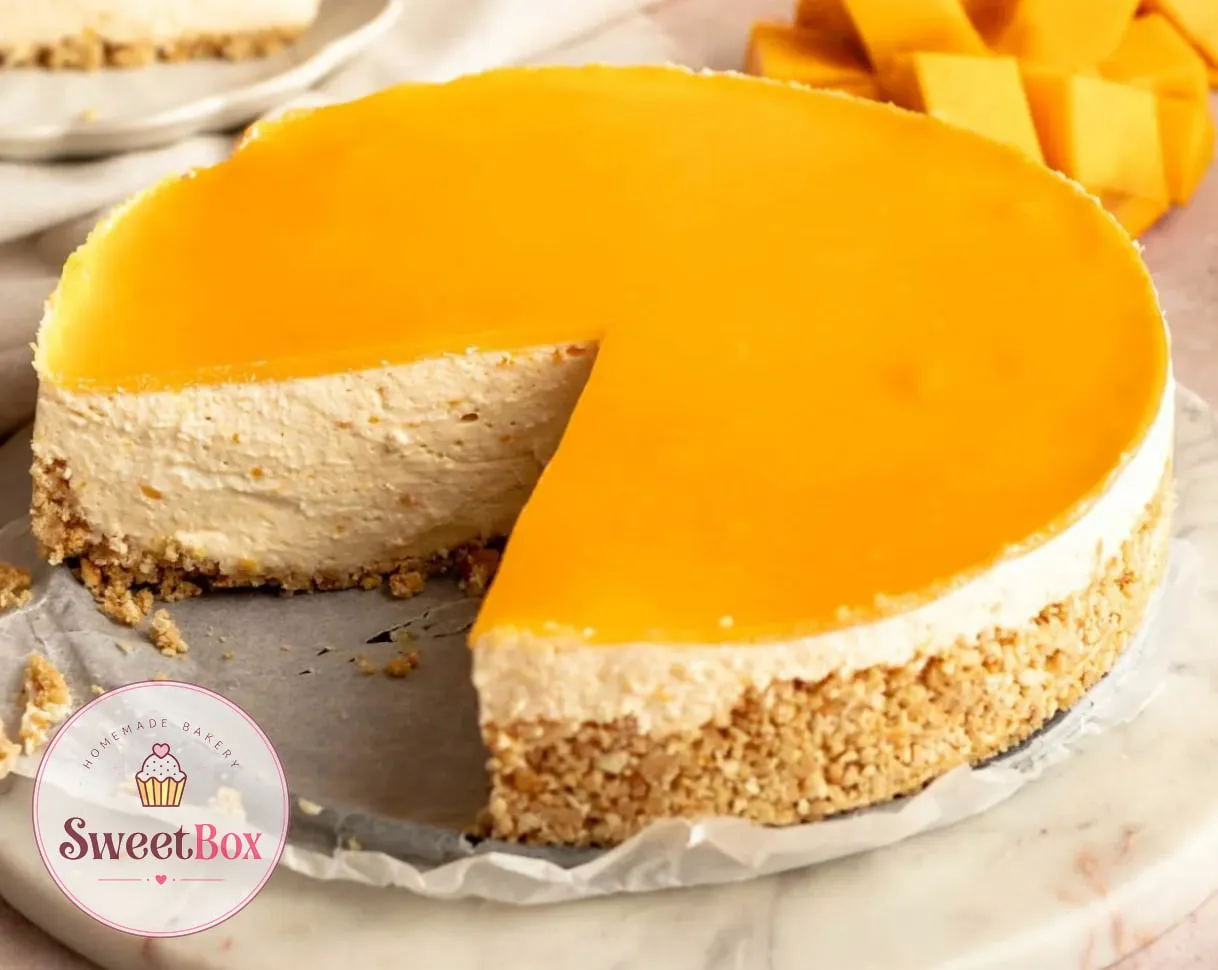 Mango cheesecake with a glossy mango glaze, one wedge cut out, next to fresh mango cubes