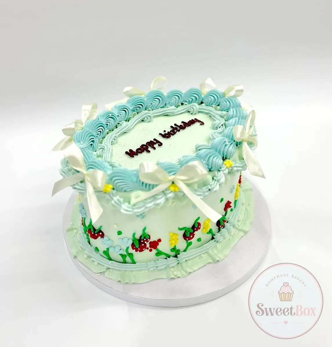 Mint and white vintage cake with blue piped frills, satin bows, painted strawberries and Happy Birthday on top