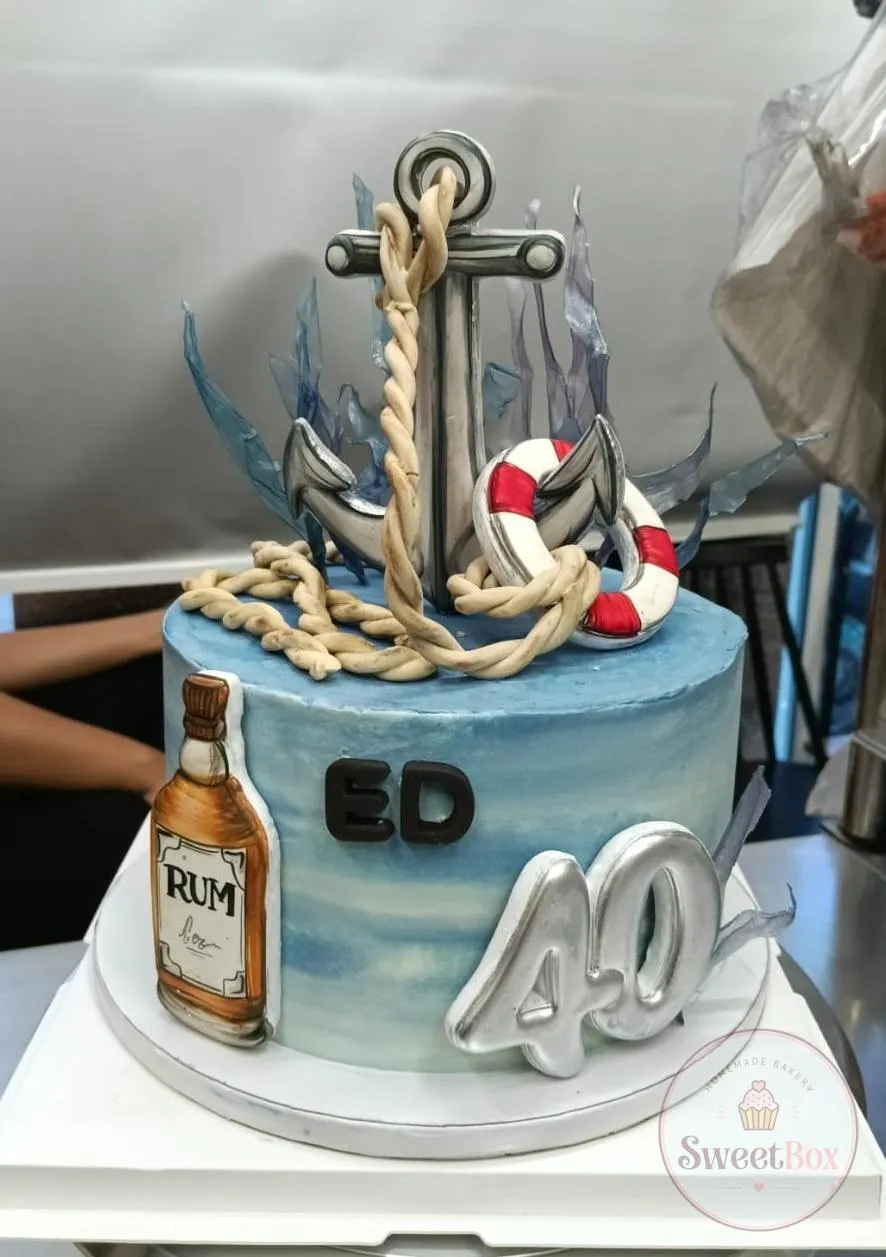 Blue nautical 40th birthday cake with an anchor, rope, life ring and a rum bottle
