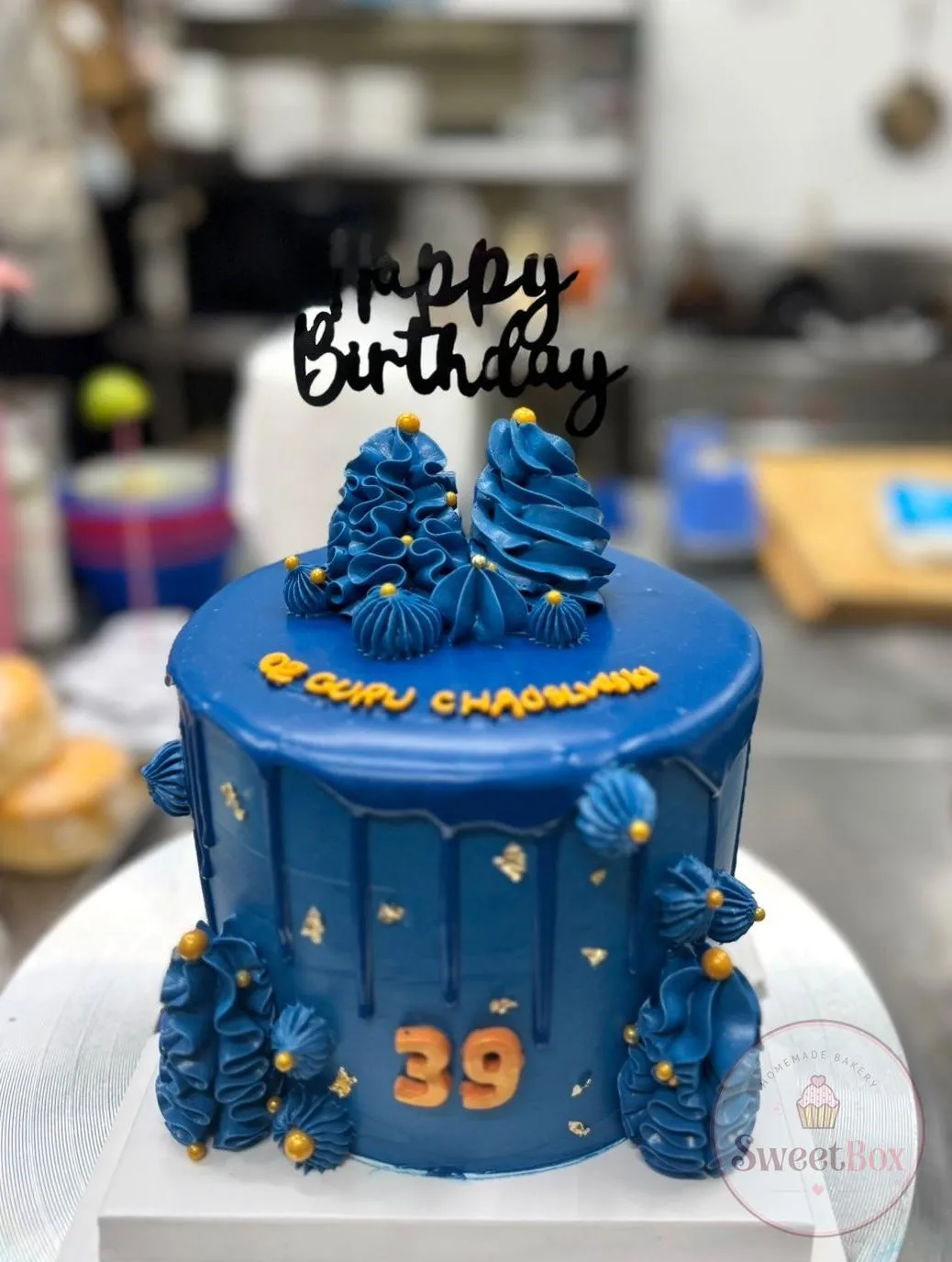 Navy blue birthday cake with piped rosettes, an orange number 39 and a Happy Birthday topper