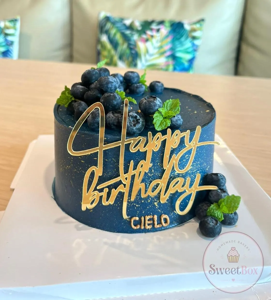 Navy cake with gold speckles, fresh blueberries and mint, a gold Happy Birthday topper and a name in gold letters