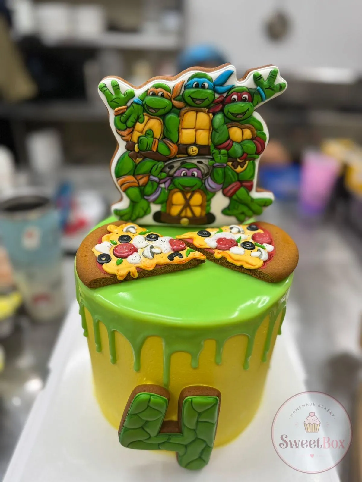 Green drip cake with a Teenage Mutant Ninja Turtles topper, pizza decorations and a number 4