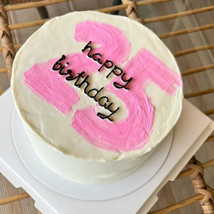 Close-up of a white bento cake with a pink number 25 and black Happy Birthday lettering