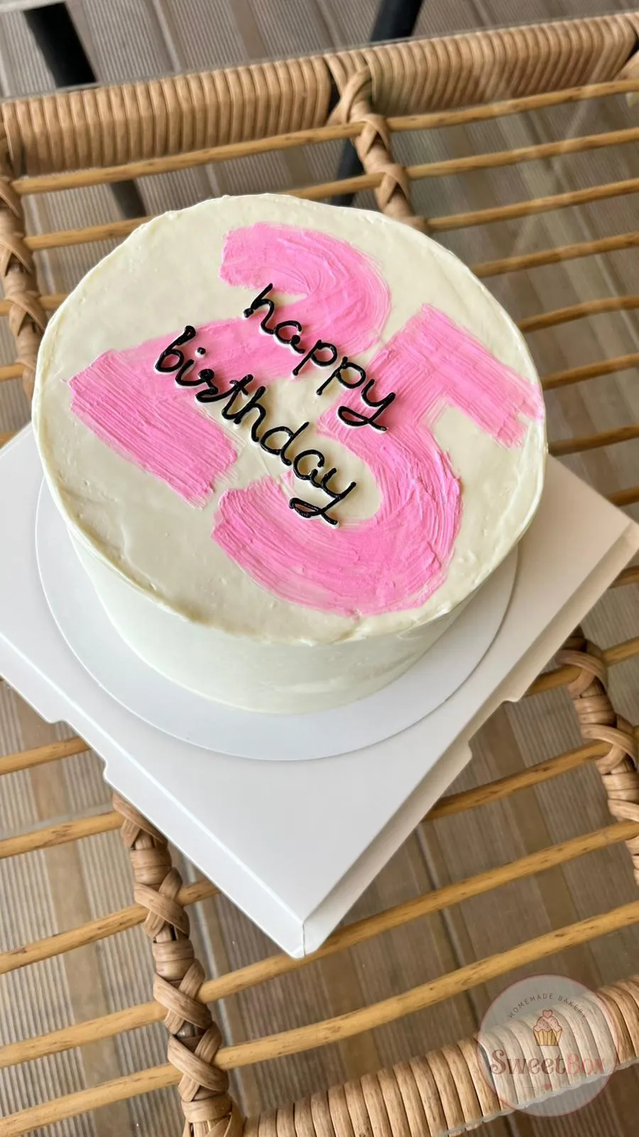 White cake with a big hand-painted pink number 25 and black Happy Birthday script on top