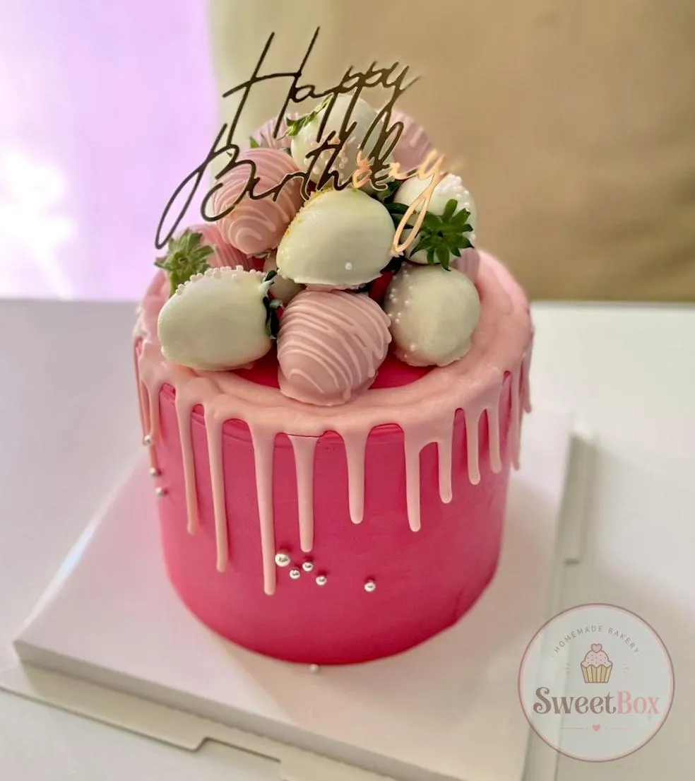 Pink drip cake crowned with chocolate-dipped strawberries, meringues and a gold topper