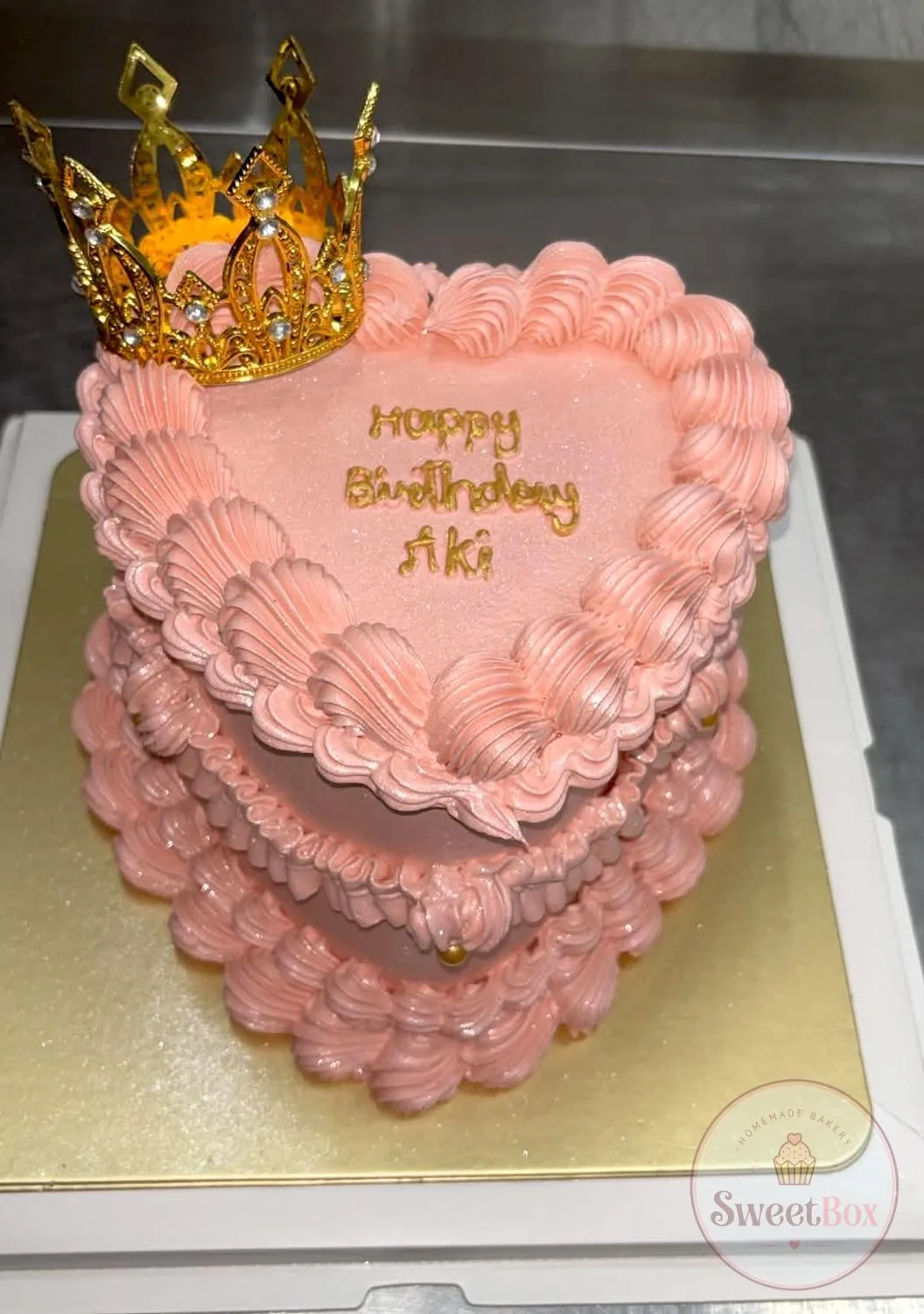 Pink heart-shaped vintage birthday cake with Happy Birthday lettering and a gold crown topper