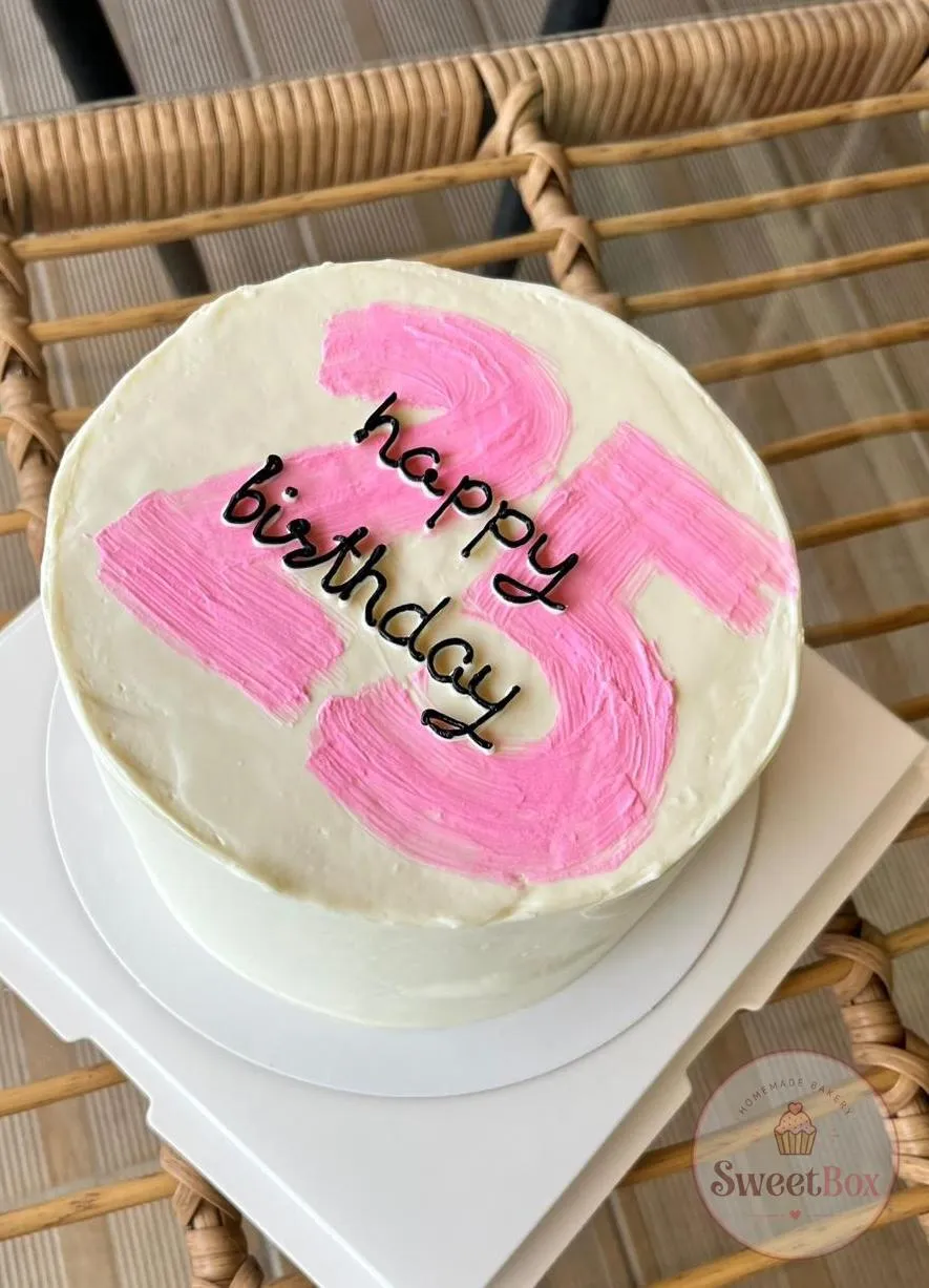 White cake with a pink buttercream number 25 and happy birthday script on top