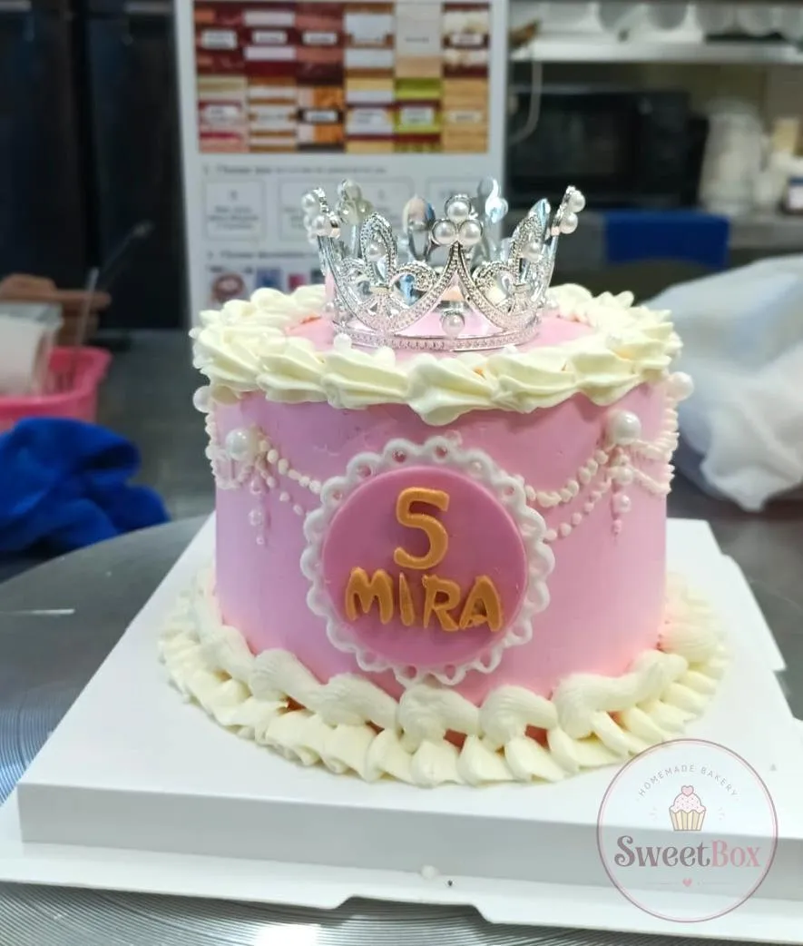 Pink princess cake with a silver tiara, cream piping, pearl garlands and a number 5 name plaque