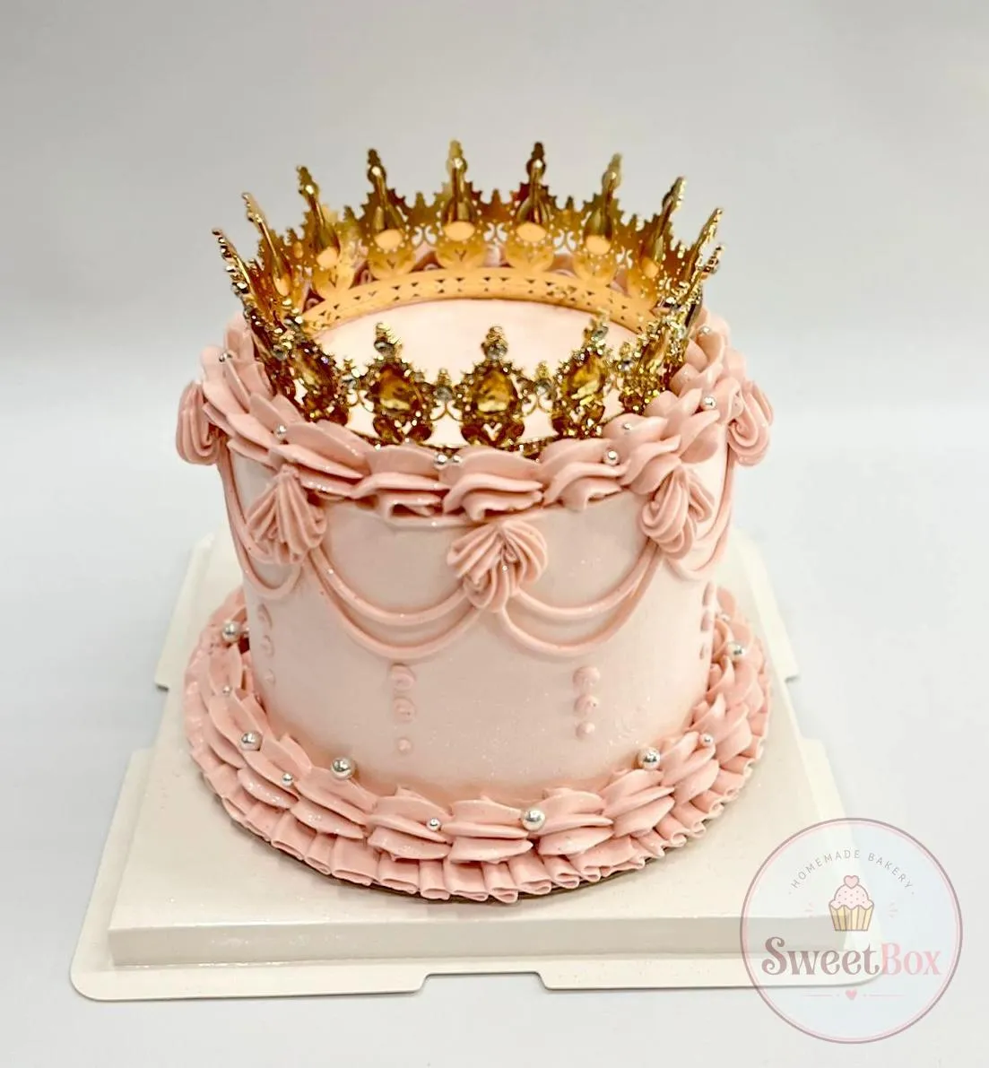 Pale pink vintage cake with ruffled piping, swags, silver pearls and a large gold jeweled crown