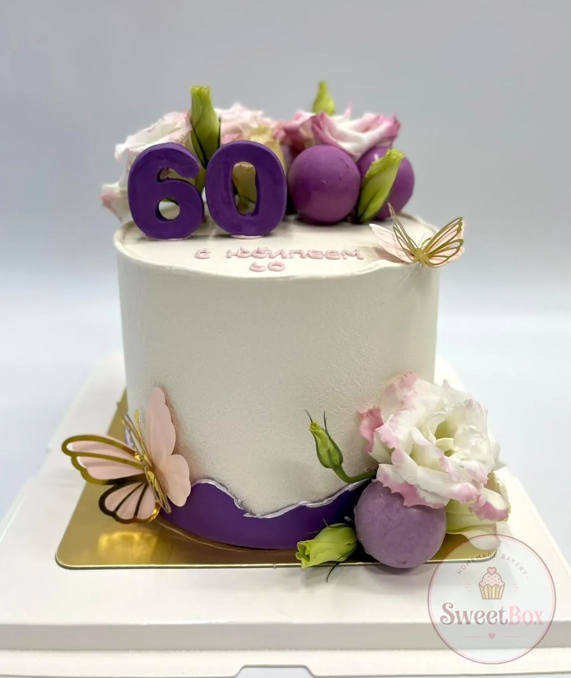 White and purple 60th birthday cake with macarons, lisianthus flowers and gold butterflies