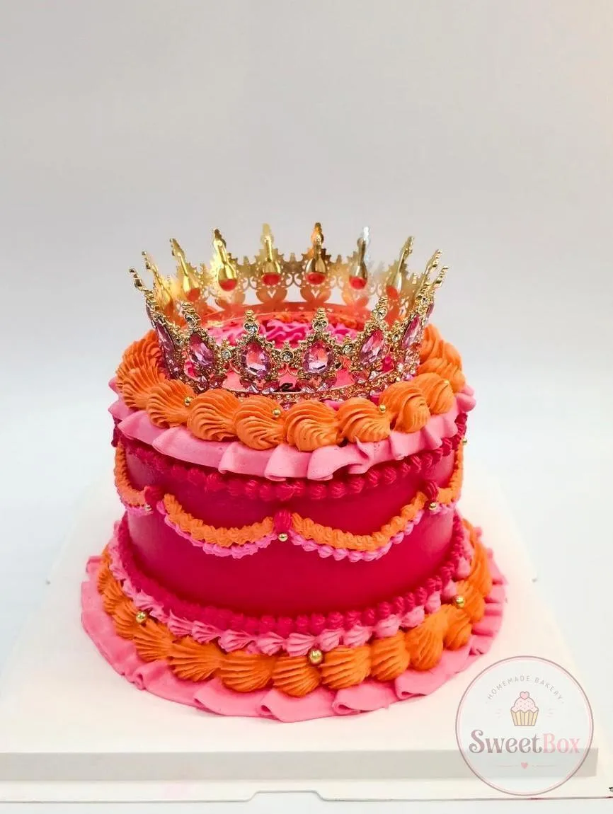Bold red, pink and orange vintage cake with ruffled piping and a gold jeweled crown