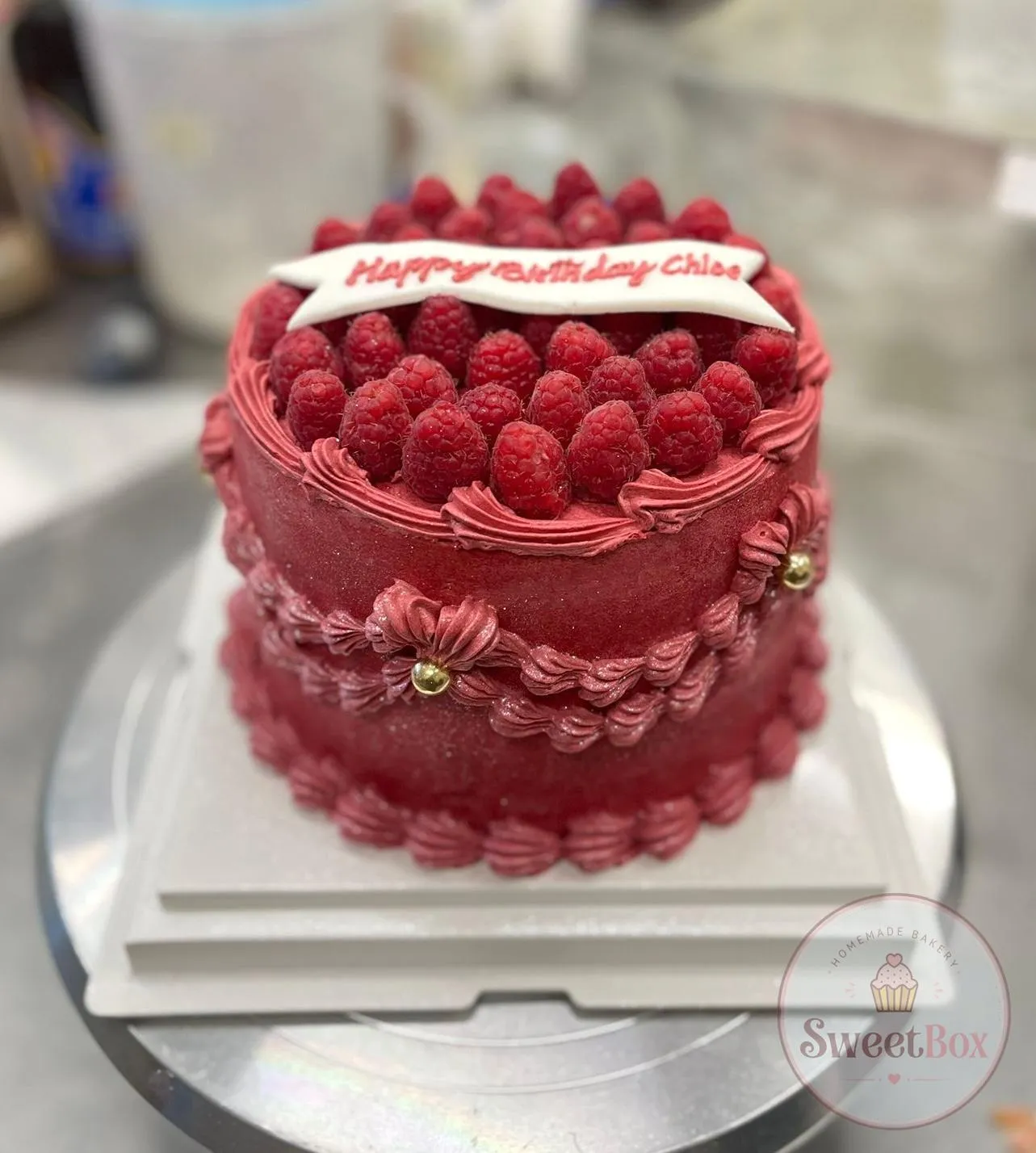Red vintage piped cake topped with raspberries and a Happy Birthday plaque