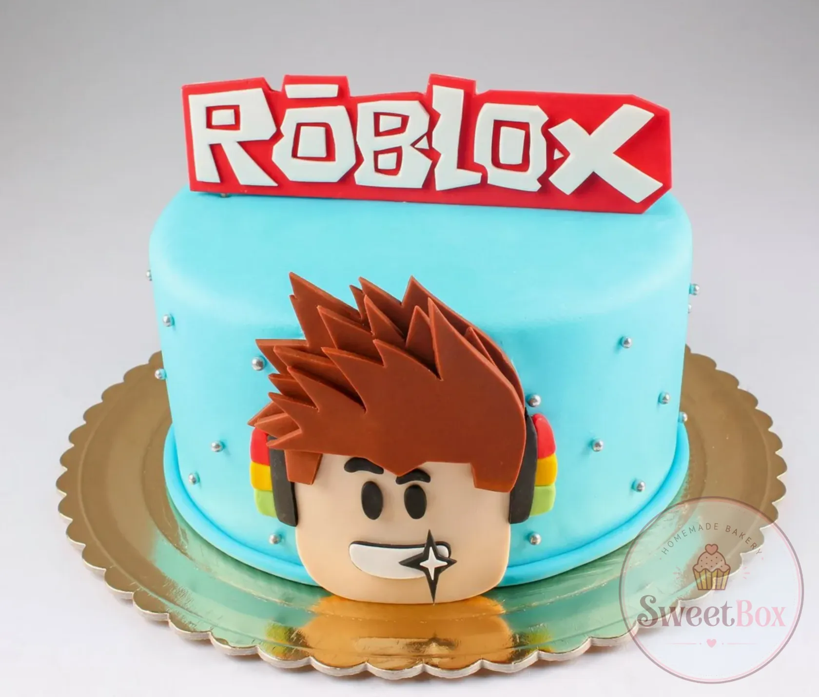 Turquoise fondant cake with a game title topper and a smiling avatar face with spiky brown hair and headphones