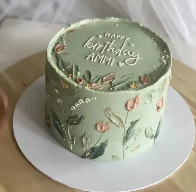 Sage green cake with palette-knife flowers and a Happy Birthday message with a name on top