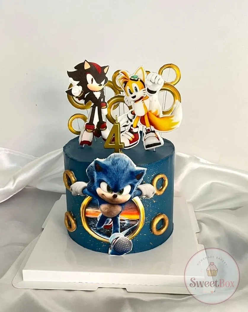Navy cake inspired by Sonic the Hedgehog with printed character toppers, gold rings and a gold number 4