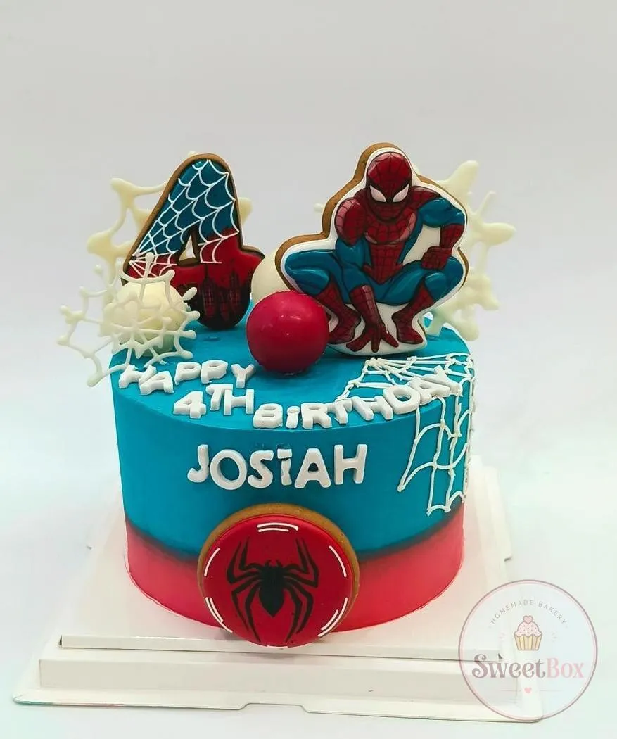 Blue and red cake with Spider-Man and number 4 cookies, white chocolate webs, a spider emblem and a child's name