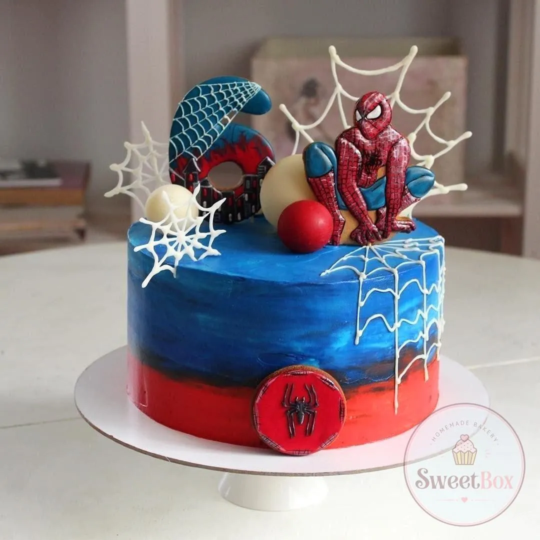 Blue and red ombre Spider-Man cake with a cookie figure, web-patterned number 6, white chocolate webs and a spider cookie