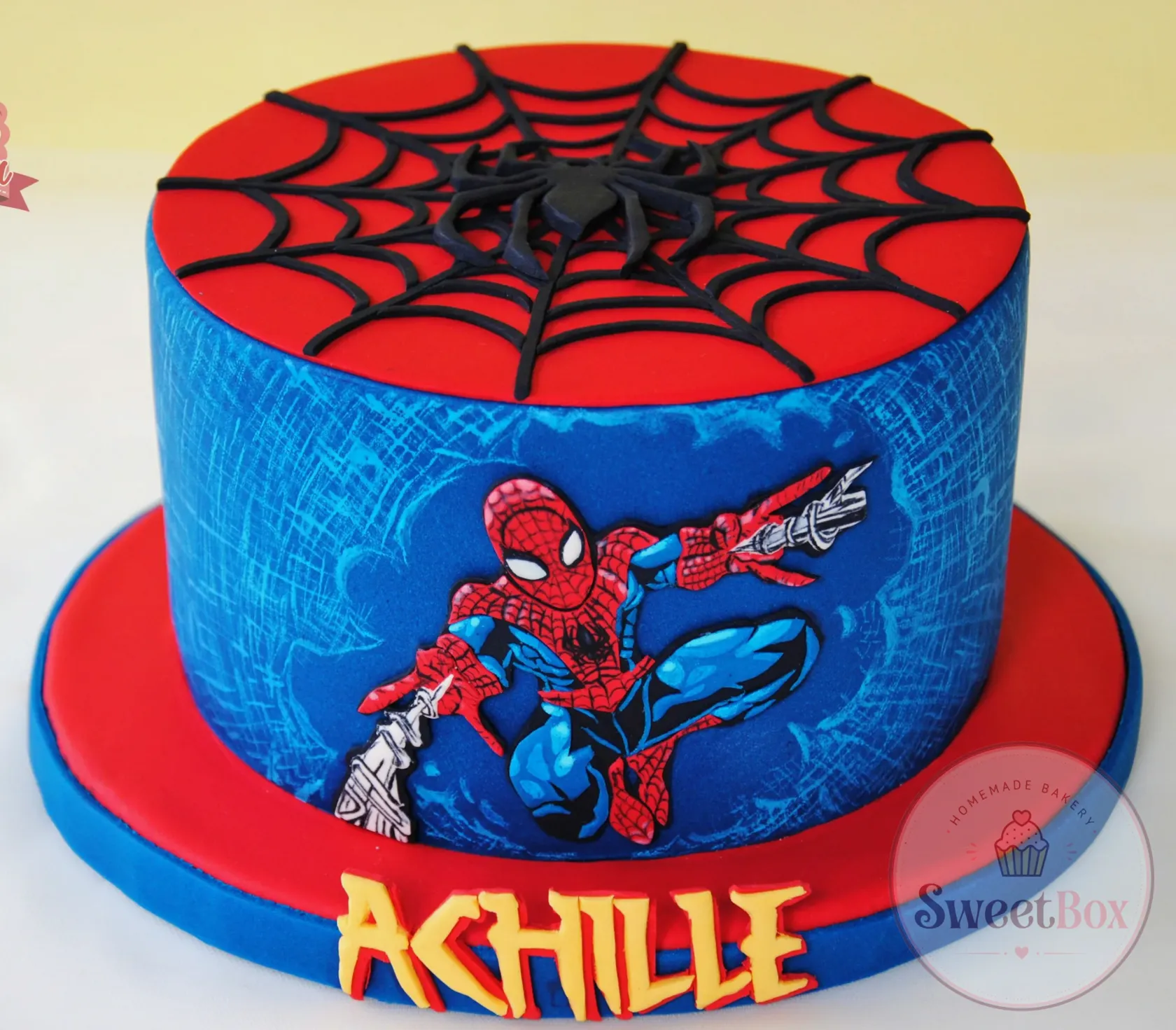 Red and blue Spider-Man cake with a spider web on top and the birthday child’s name in yellow letters