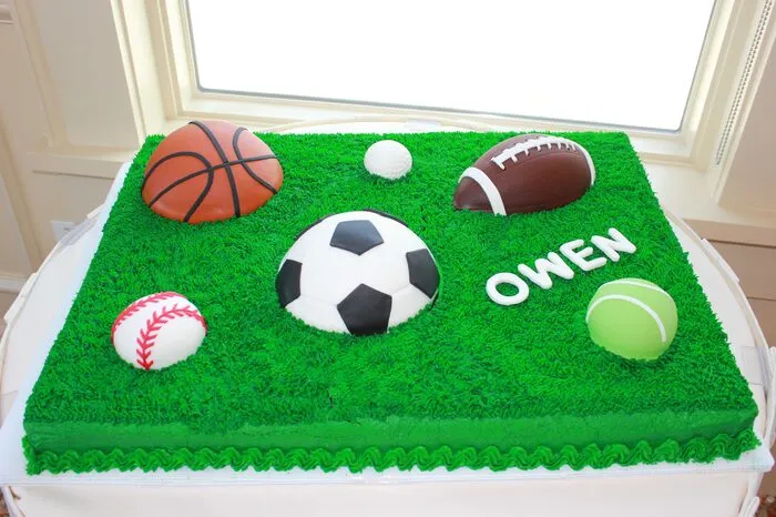 Green grass sheet cake with fondant soccer, basketball, football, baseball and tennis balls and a name