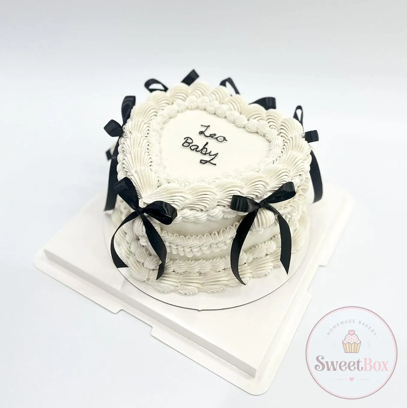 White heart-shaped vintage cake with ruffled piping, black ribbon bows and a handwritten message