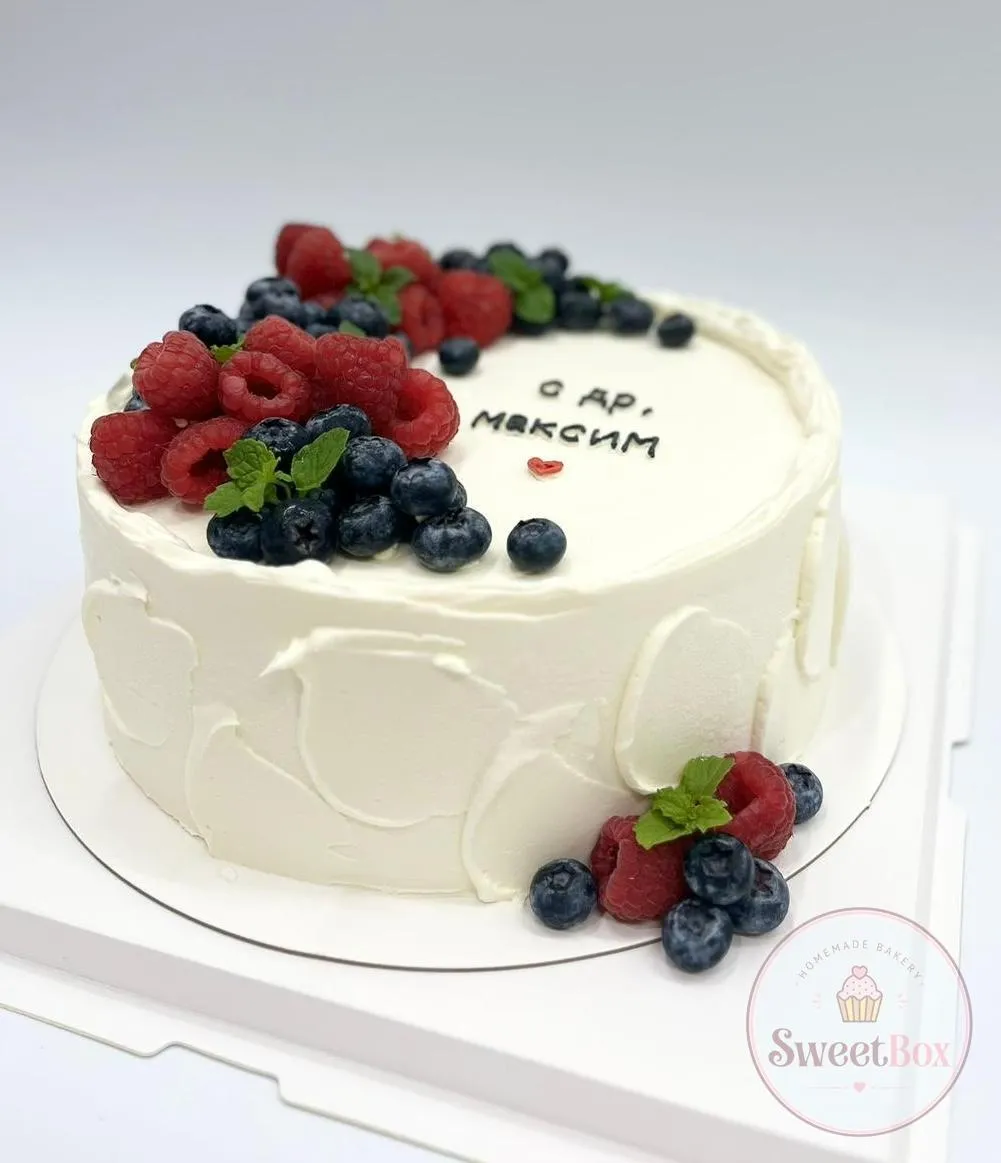White textured cake with clusters of raspberries, blueberries and mint and a short handwritten greeting