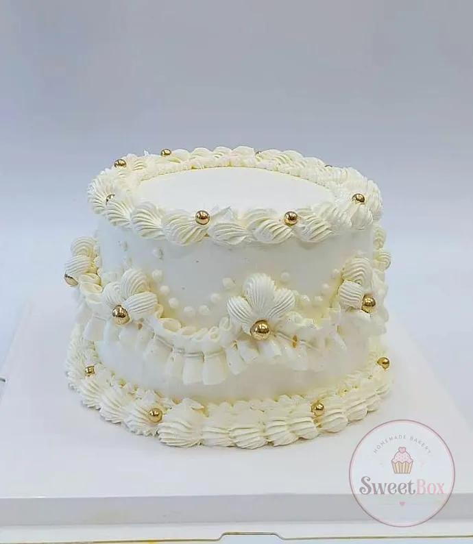 All-white vintage Lambeth-style cake with layered piped frills, swags and gold pearls